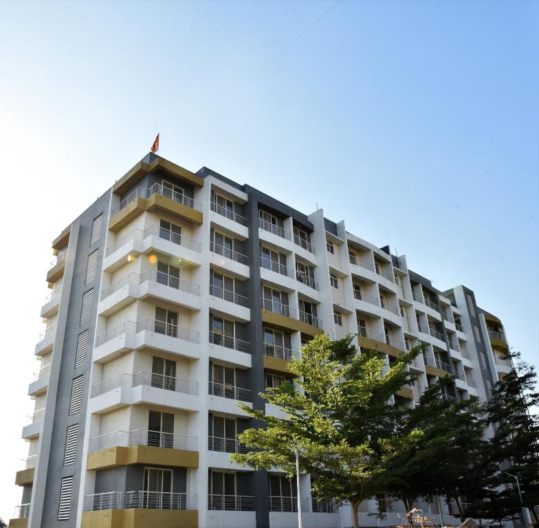 un edificio blanco alto con un árbol delante de él en Starlit Suites Shirdi, en Nighoj