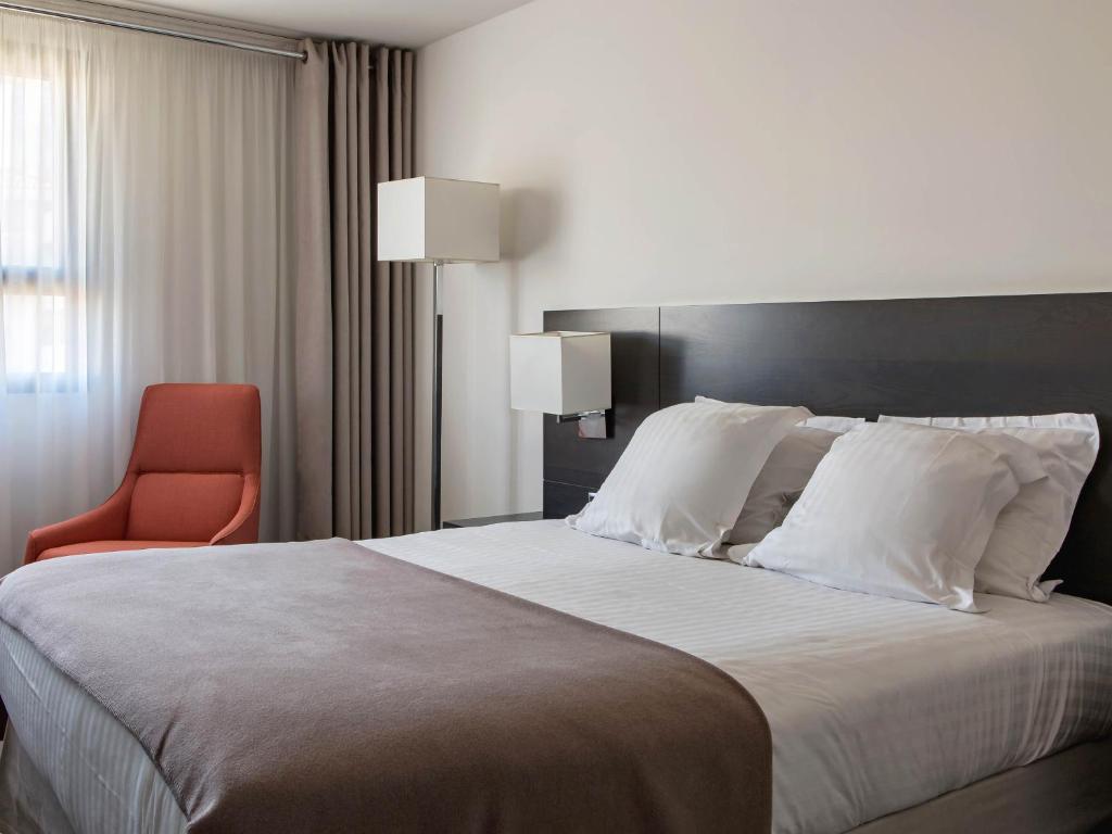 a bedroom with a large bed and a red chair at New Hotel of Marseille - Vieux Port in Marseille