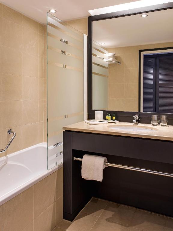 a bathroom with a tub and a sink and a mirror at New Hotel of Marseille - Vieux Port in Marseille