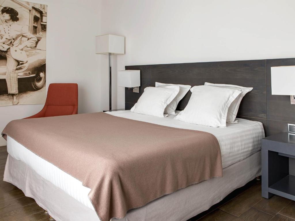 a bedroom with a large bed and a red chair at New Hotel of Marseille - Vieux Port in Marseille