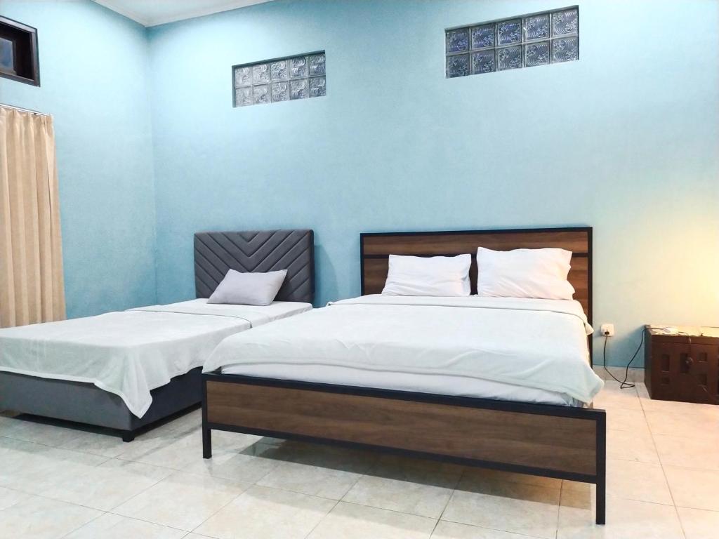 2 camas en una habitación con paredes azules en Loven Sanur Guest House, en Sanur