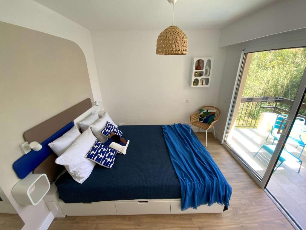 a bedroom with a bed with blue sheets and a window at Appartement Le Lavandou, 2 pièces, 4 personnes - FR-1-308-175 in Le Lavandou