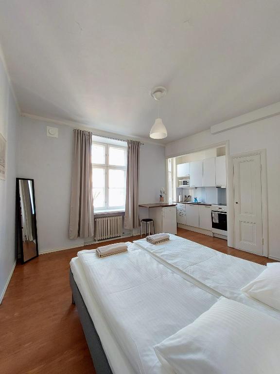 a large white bed in a room with a kitchen at Studio Mansku in Helsinki