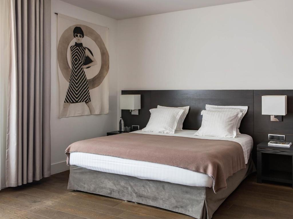a bedroom with a large bed and a painting of a woman at New Hotel of Marseille - Vieux Port in Marseille