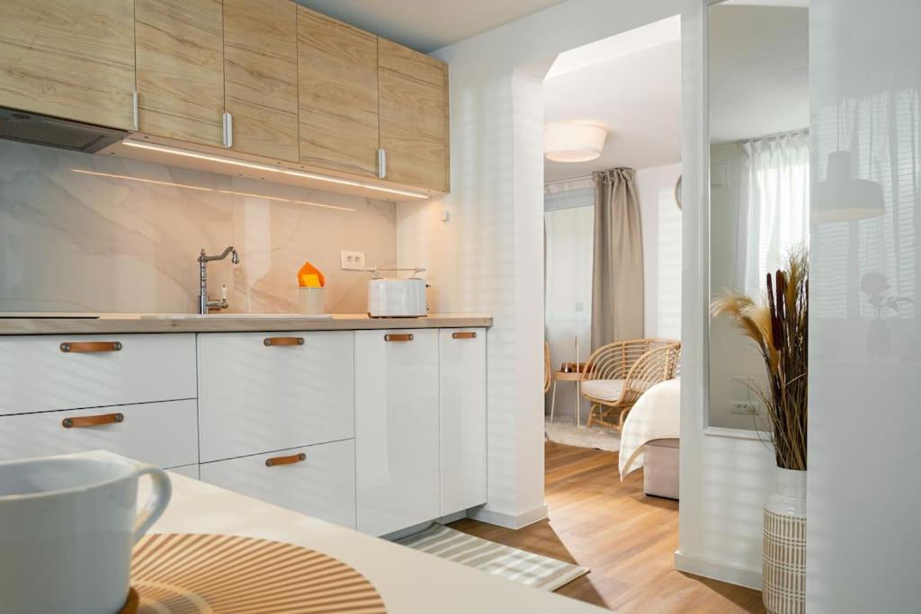 une cuisine avec des armoires blanches et un lit dans une chambre dans l'établissement New Cute Studioapartment in Ljubljana + Free bikes, à Ljubljana