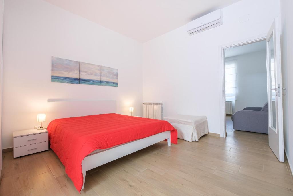 ein weißes Schlafzimmer mit einem roten Bett und einem Sofa in der Unterkunft Casa Vacanza Messina in Messina