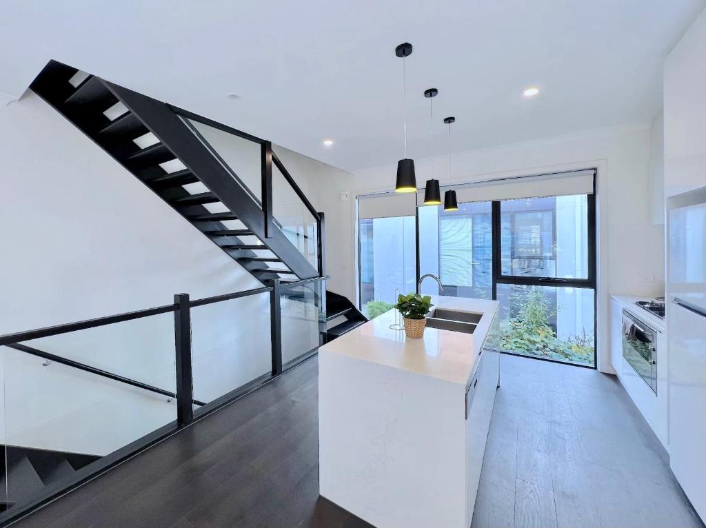 une cuisine blanche avec un escalier dans une maison dans l'établissement Modern 3-level Townhouse FreeParking, à Melbourne