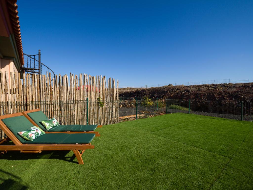 einen Stuhl auf einem Rasen neben einem Zaun in der Unterkunft Private Terrace Majanicho Home -Garden & Pool in La Oliva