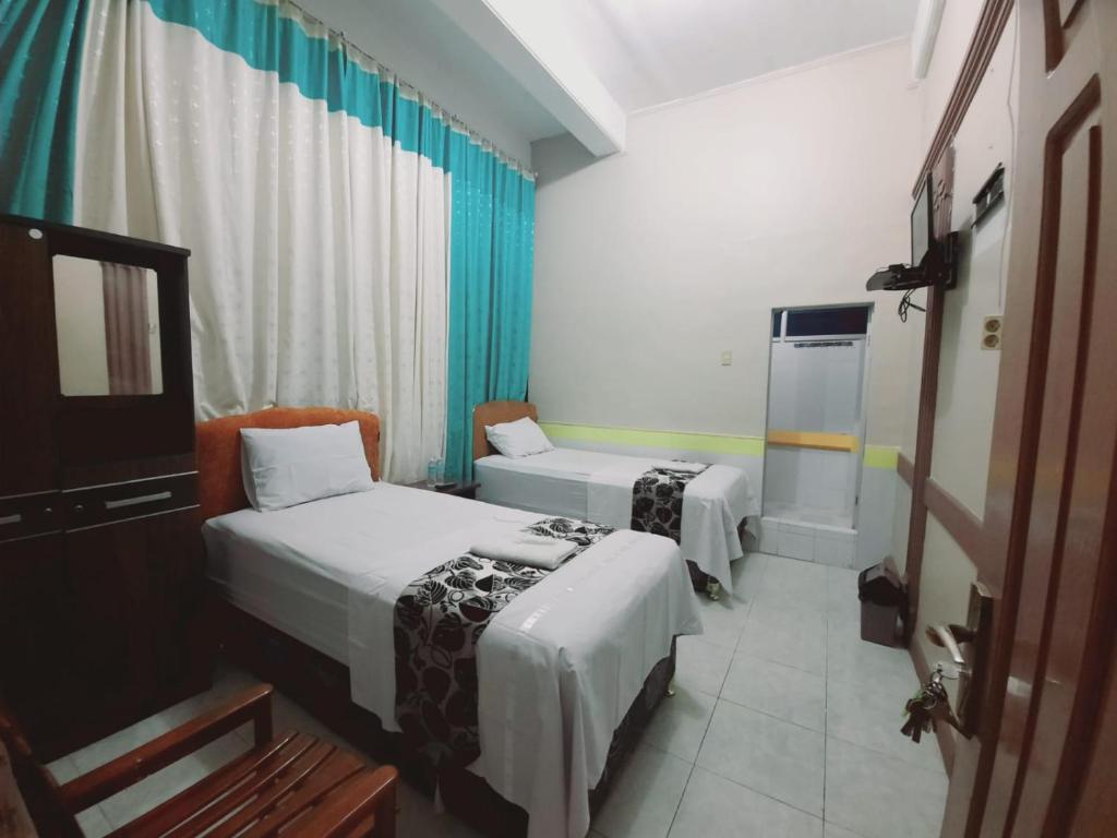 a hotel room with two beds and a television at Hotel Meurah Mulia Syariah in Banda Aceh