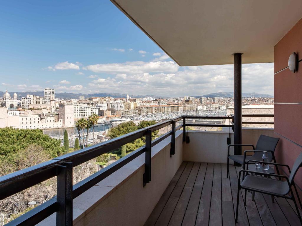 a balcony with two chairs and a view of a city at New Hotel of Marseille - Vieux Port in Marseille