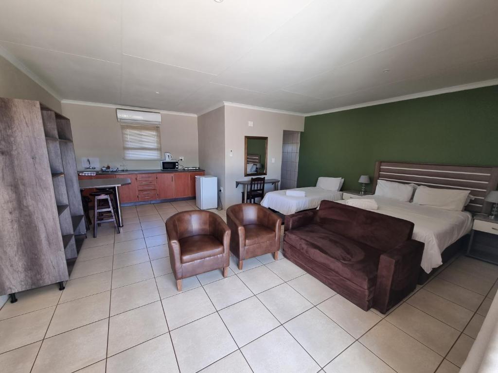 a bedroom with a bed and a couch and a kitchen at Pro Plants Accommodation in Kimberley
