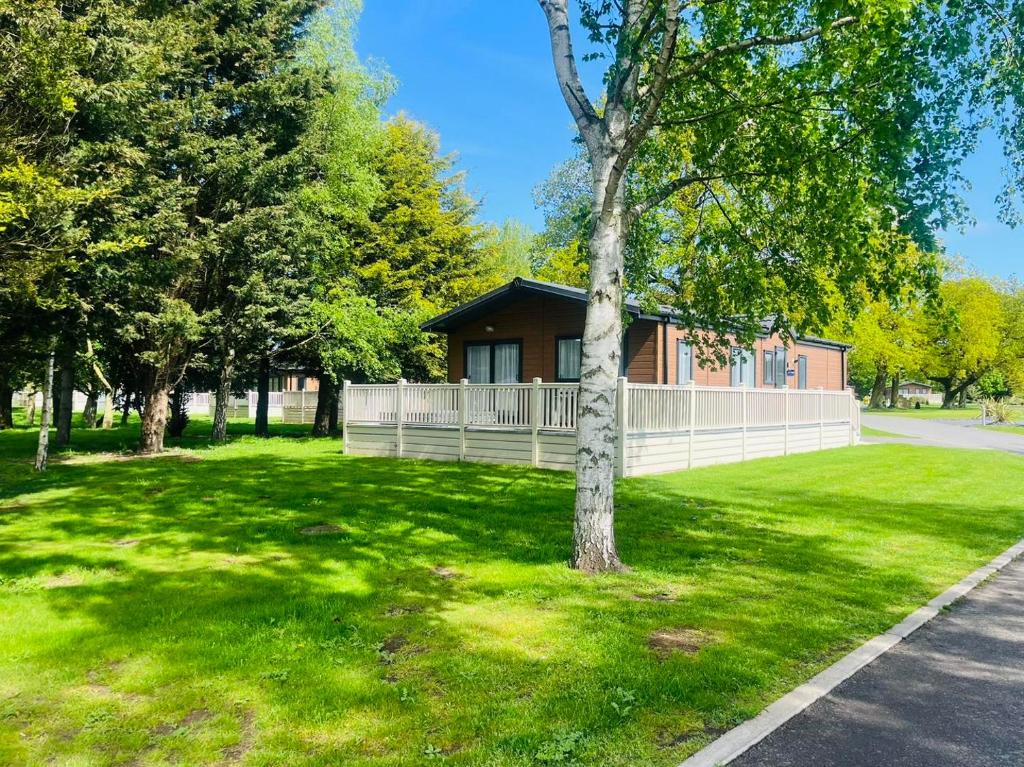 a house on a green lawn with a tree at Lotus Lodge with Hot Tub in York