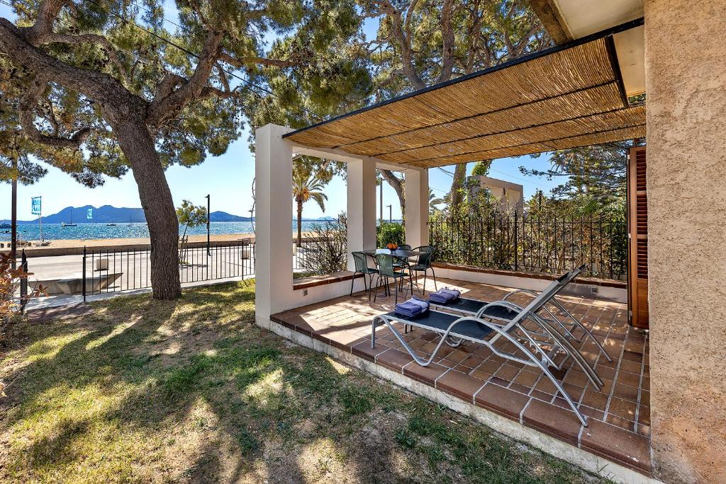 une terrasse avec une chaise, une table et un arbre dans l'établissement LA GOLA APARTMENT, First-line Beachfront, Newly Refurbished, à Port de Pollença