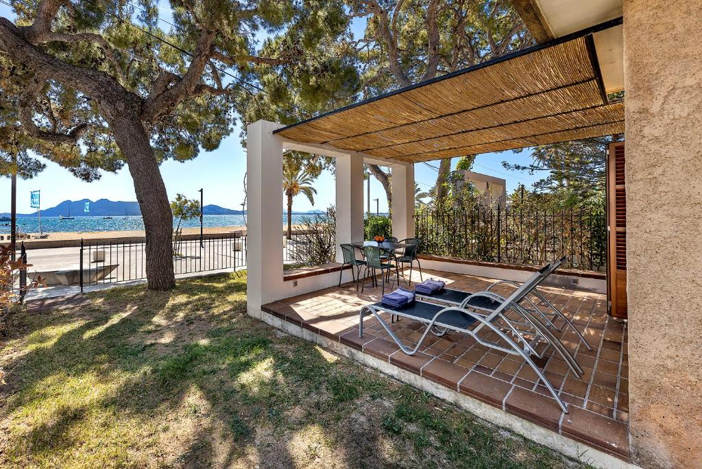 a patio with a chair and a table and a tree at LA GOLA APARTMENT, First-line Beachfront, Newly Refurbished in Port de Pollensa