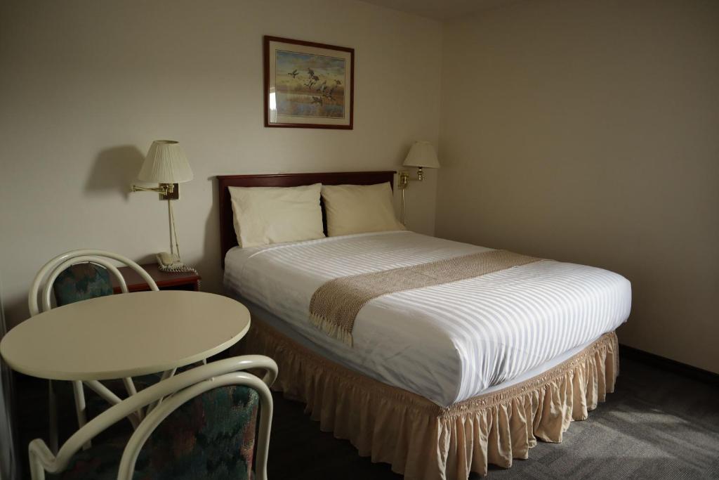 a bedroom with a bed and a table and a table at Destination Family Hotel in Whitehorse