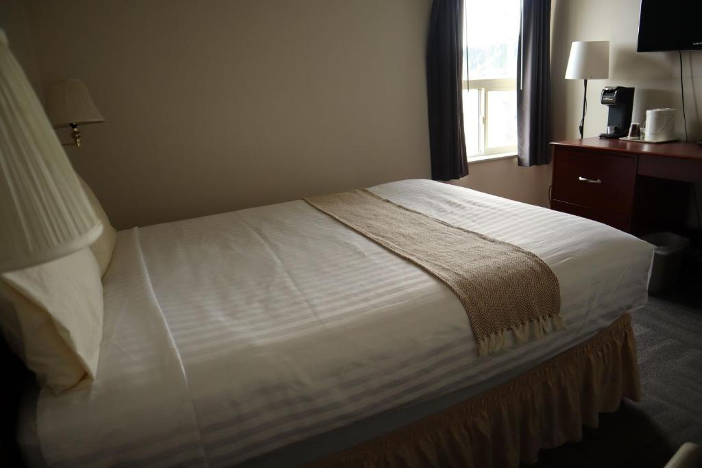 a bed in a hotel room with a window at Destination Family Hotel in Whitehorse