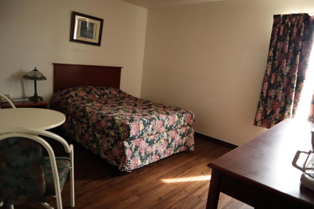 a hotel room with a bed and a table at Destination Family Hotel in Whitehorse