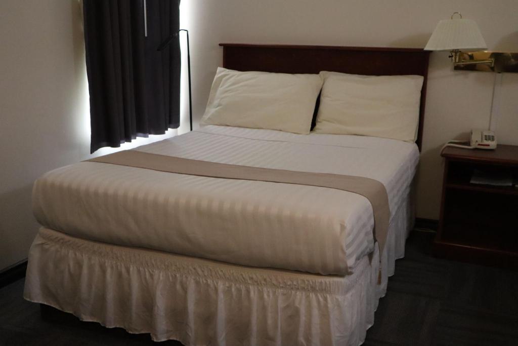 a large bed in a hotel room with a window at Destination Family Hotel in Whitehorse