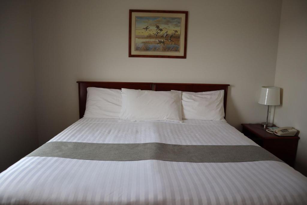 ein Bett in einem Schlafzimmer mit einem Bild an der Wand in der Unterkunft Destination Family Hotel in Whitehorse