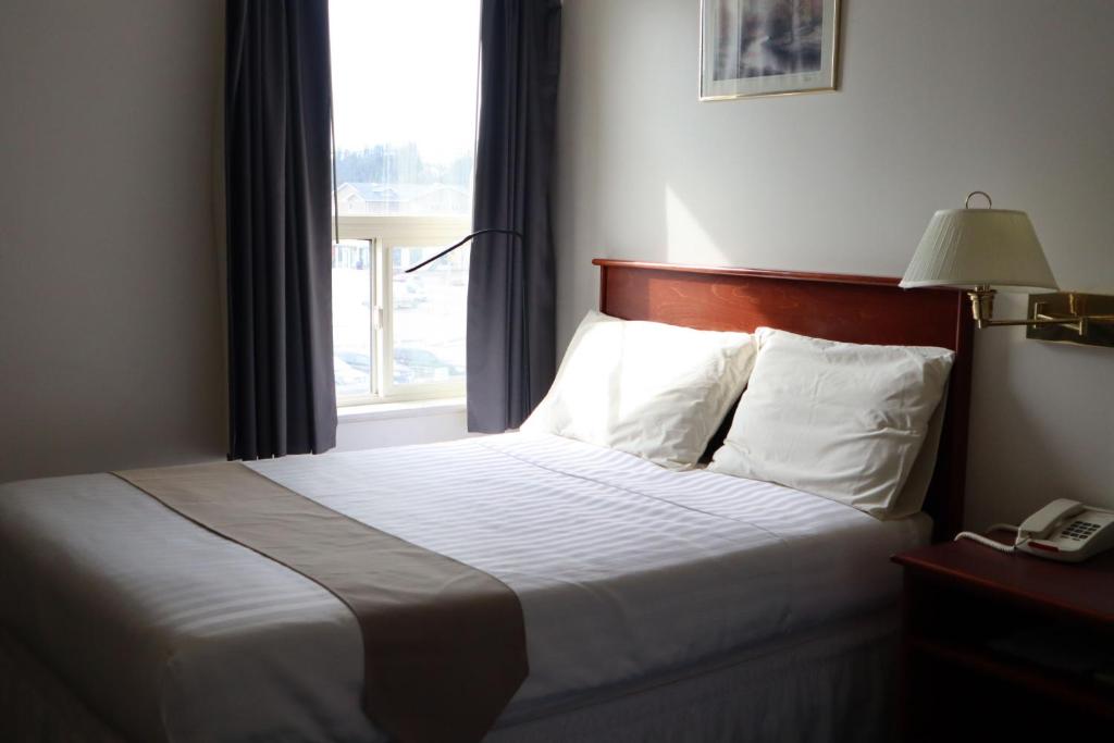 a bed in a hotel room with a window at Destination Family Hotel in Whitehorse