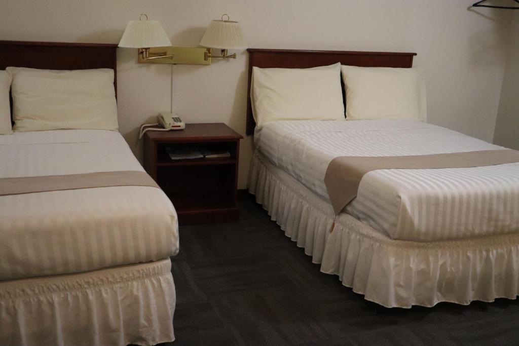 a hotel room with two beds and a telephone at Destination Family Hotel in Whitehorse