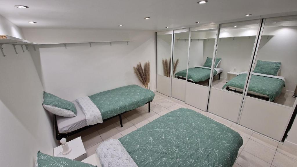 een kamer met 2 spiegels en een groene bank bij Sous-sol aménagé tout équipé avec jardin & parking in Berteaucourt-les-Dames
