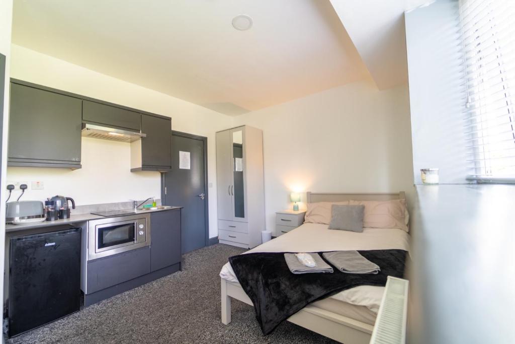 a small bedroom with a bed and a kitchen at Spacious 1-Bed Studio in Birmingham in Birmingham