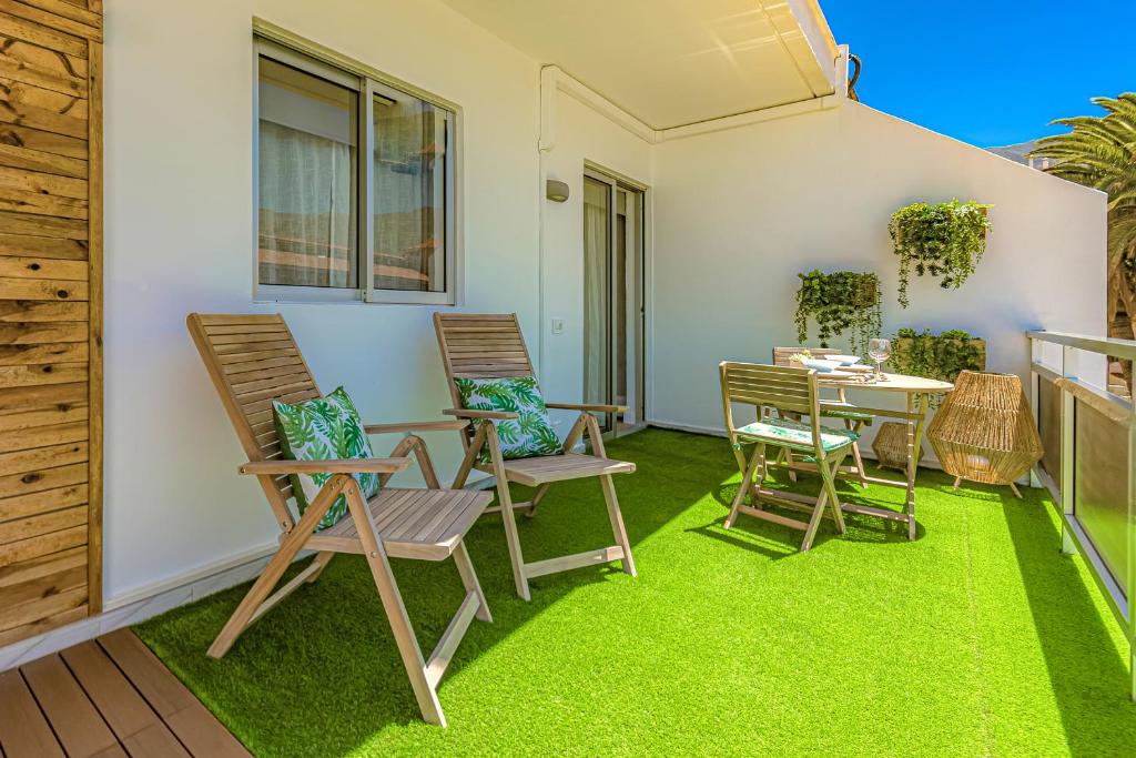 a patio with chairs and a table and grass at Vista al Teide y al mar 7 in Puerto de la Cruz