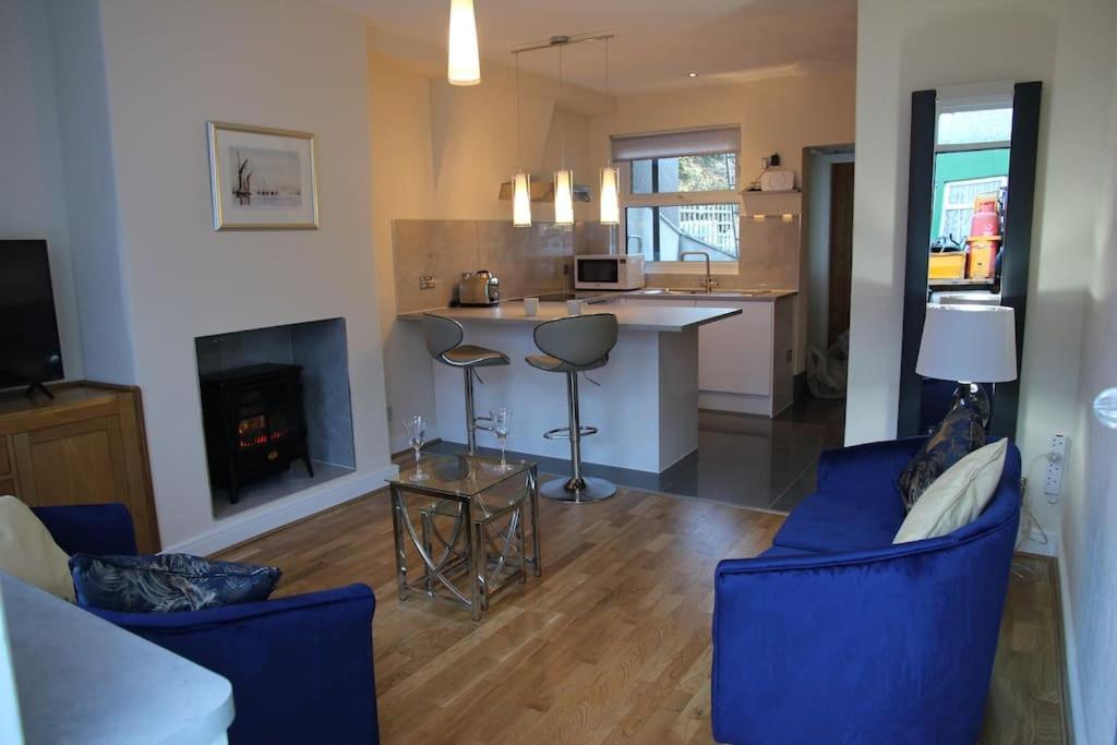 a kitchen and living room with blue chairs and a fireplace at Charming Mid Terrace Cottage in Conwy