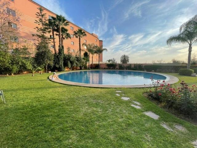 een zwembad in een tuin naast een gebouw bij APPARTEMENT MARRAKECH HIVERNAGE in Marrakesh