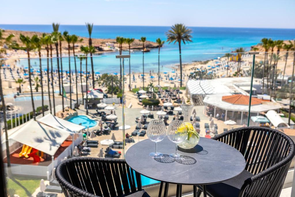 uma mesa com copos de vinho e vista para a praia em Pavlo Napa Beach Hotel em Agia Napa