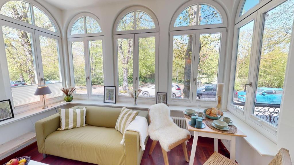 un soggiorno con divano e un mucchio di finestre di Villa Parkblick a Rostock