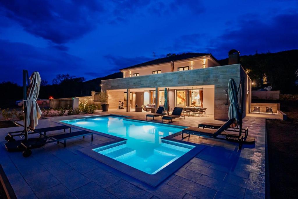 a swimming pool in front of a house at night at Villa Vitrenik, Cista Velika, Makarska-Imotski in Velika Cista