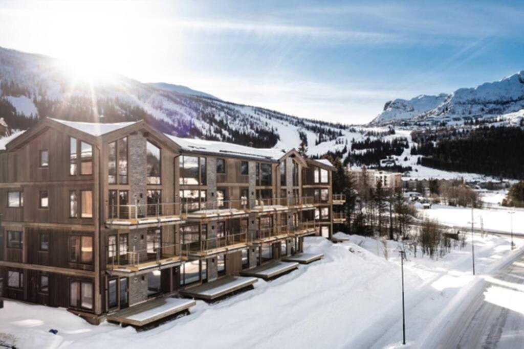 a building in the snow with the mountains in the background at Fjellnest Hemsedal in Hemsedal