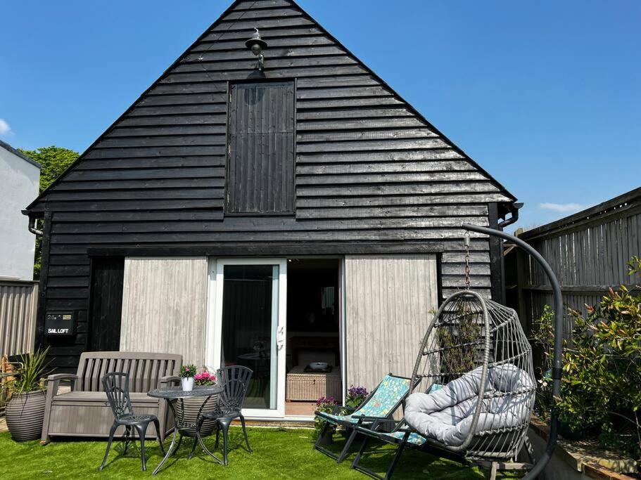 una casa negra con un columpio en un patio en Quirky 1 bedroom barn on the river in Arundel, en Arundel