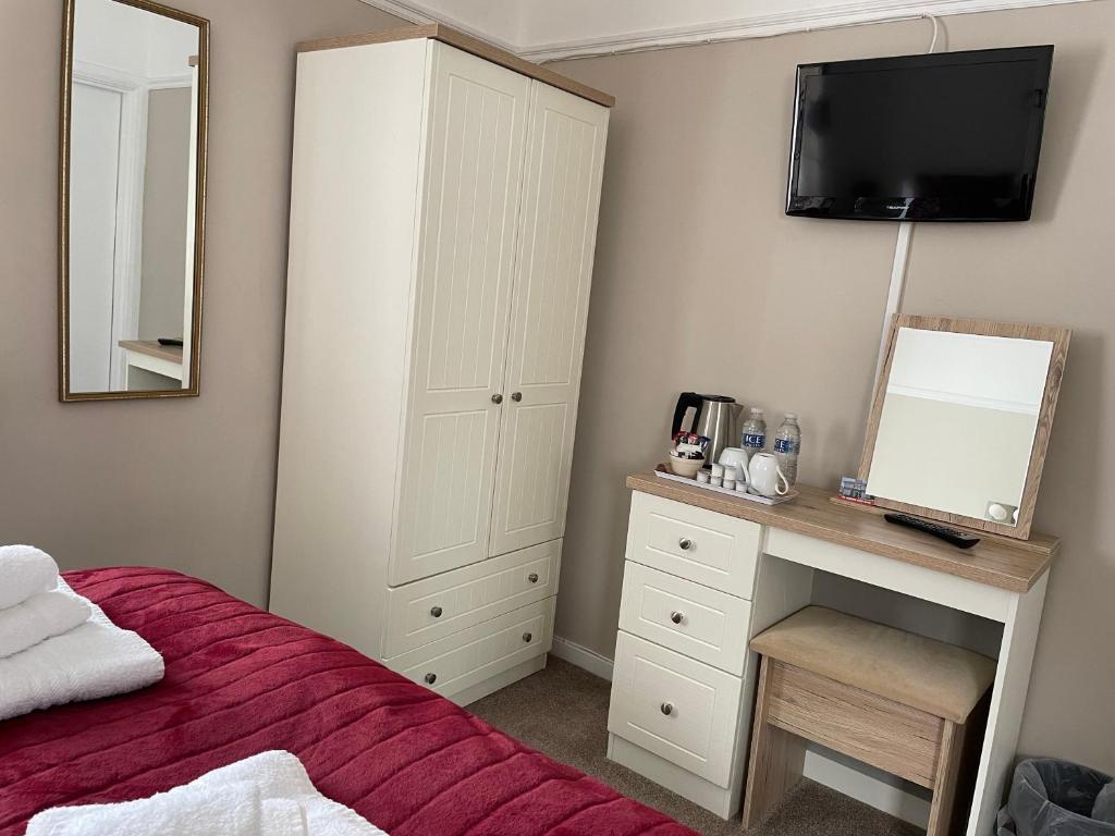 a bedroom with a bed and a dresser with a mirror at The Sandrock in Clacton-on-Sea