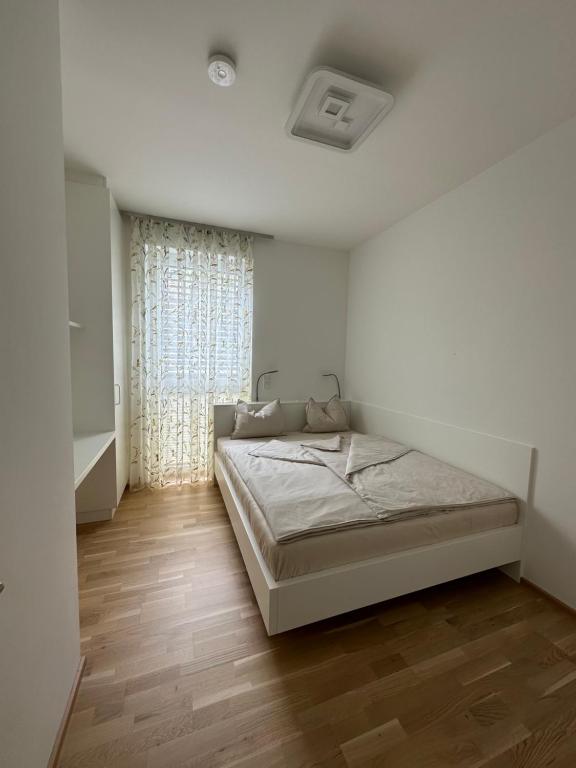 ein weißes Schlafzimmer mit einem Bett und einem Fenster in der Unterkunft Himmelblau by Strandclub Velden in Velden am Wörthersee