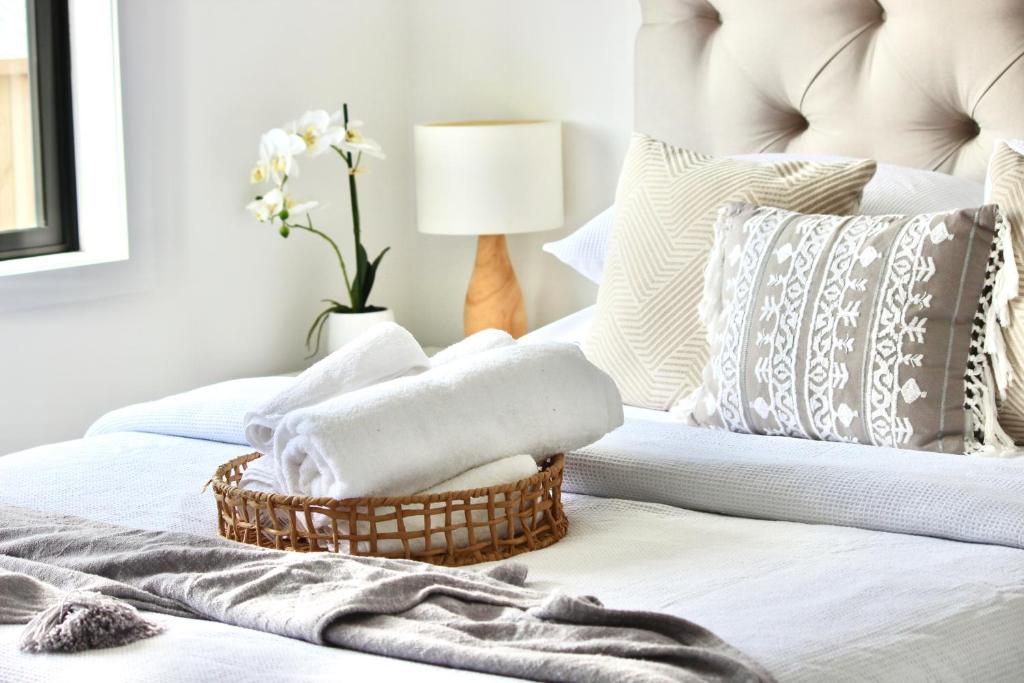 a bedroom with a bed with a basket of towels at Zen hideaway in Aotea in Porirua