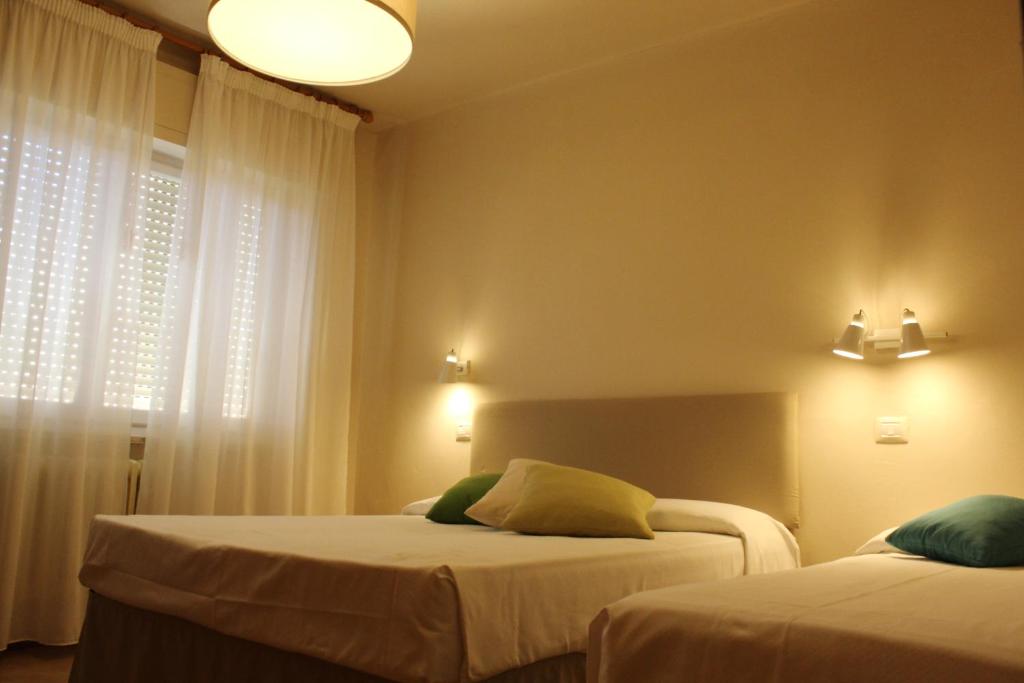 a bedroom with two beds and a window at Hotel Ristorante Il Gabbiano in Cecina
