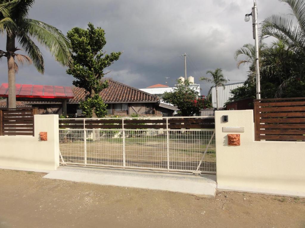 a white fence with a gate in front of a house at Ishigakijima Akagawara Villa in Ishigaki Island