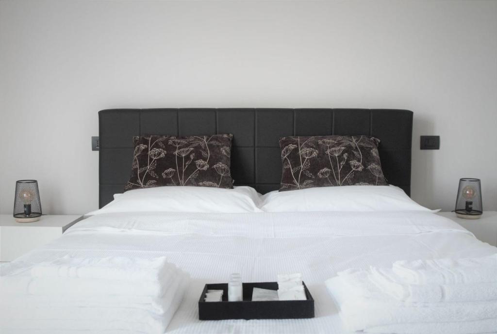 Una cama con cabecero negro con una bandeja. en 7 LAKES Aparthotel, en Burolo