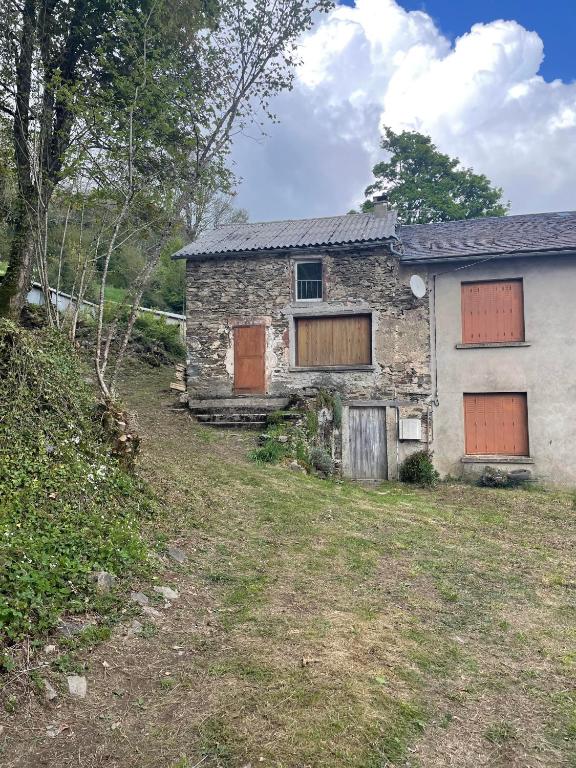 une vieille maison en pierre avec des fenêtres barricadées dans une cour dans l'établissement La maison de Cabannes, à Moulin-Mage