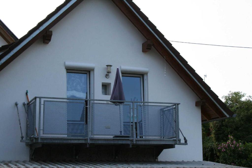 a white house with a balcony with an umbrella at Breig,s Ferienwohnung in Broggingen