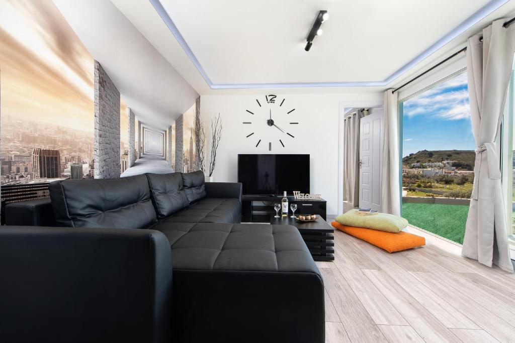 a living room with a black couch and a clock at GR House Eleftheria in Afantou