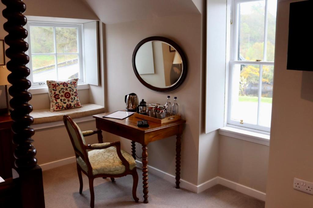 Cette chambre comprend une table, un miroir et une chaise. dans l'établissement Tigh an Truish Inn, à Oban