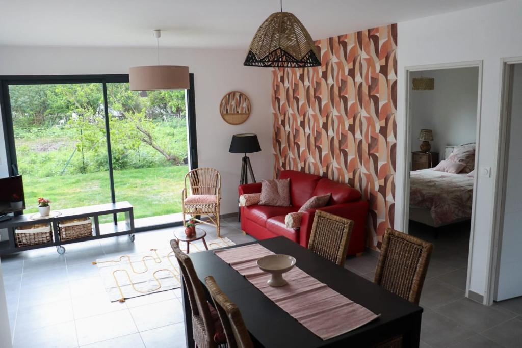 uma sala de estar com um sofá vermelho e uma mesa em Charmante Maison neuve au Lac d'Hourtin em Hourtin