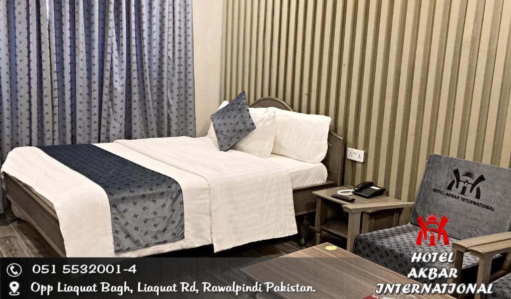 a hotel room with a bed and a chair at Hotel Akbar International in Rawalpindi