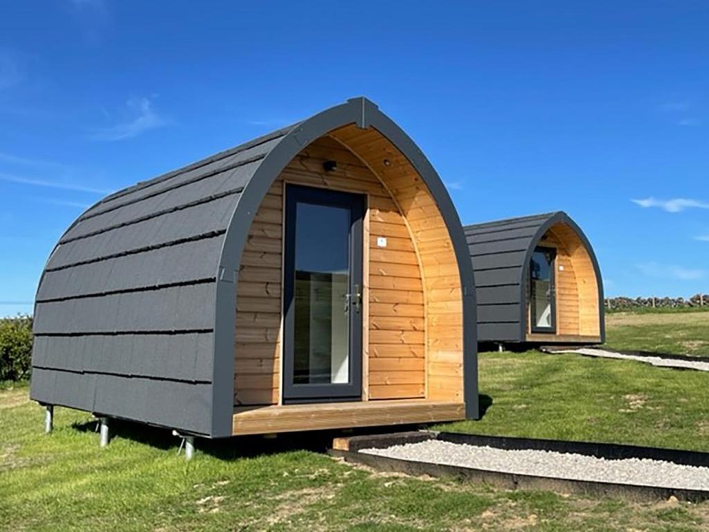 two small buildings sitting on top of a field at F&H Camping in Danby