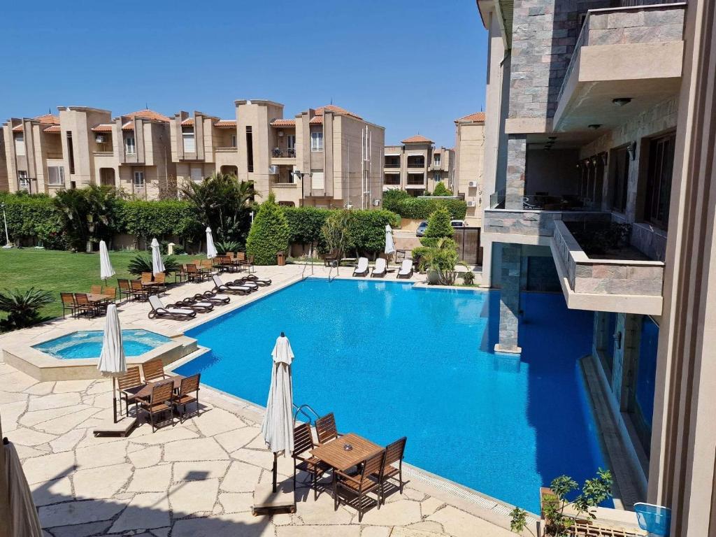 a large swimming pool with chairs and umbrellas at Panacea Suites Hotel in Borg El Arab
