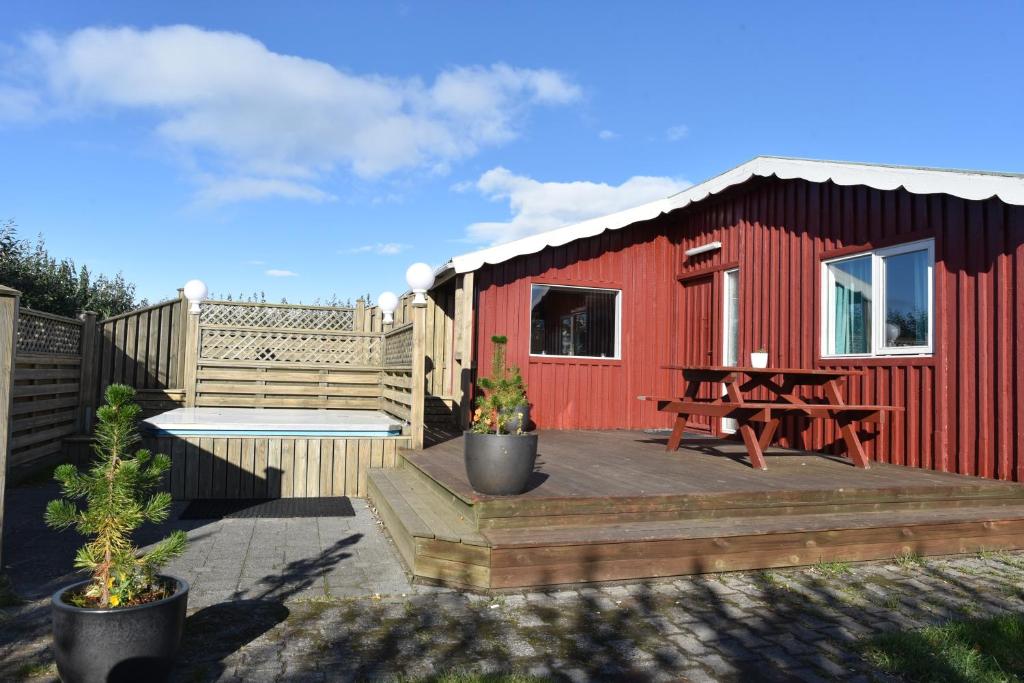 a red shed with a picnic table and a wooden deck at Laxás Cottage in Blönduós
